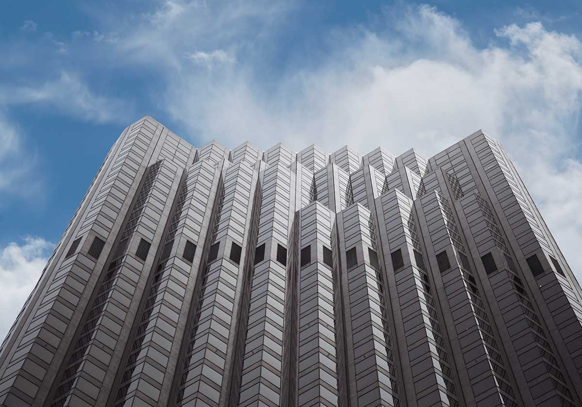 A gray building with windows in the middle. Blue sky with clouds is in the background.