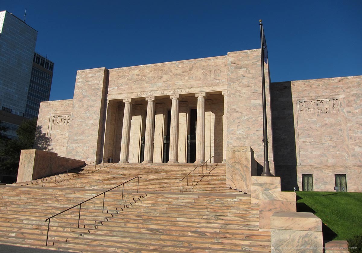 A beige square building with stairs leading up to 4 columns. It is called the Joslyn Art Museum.