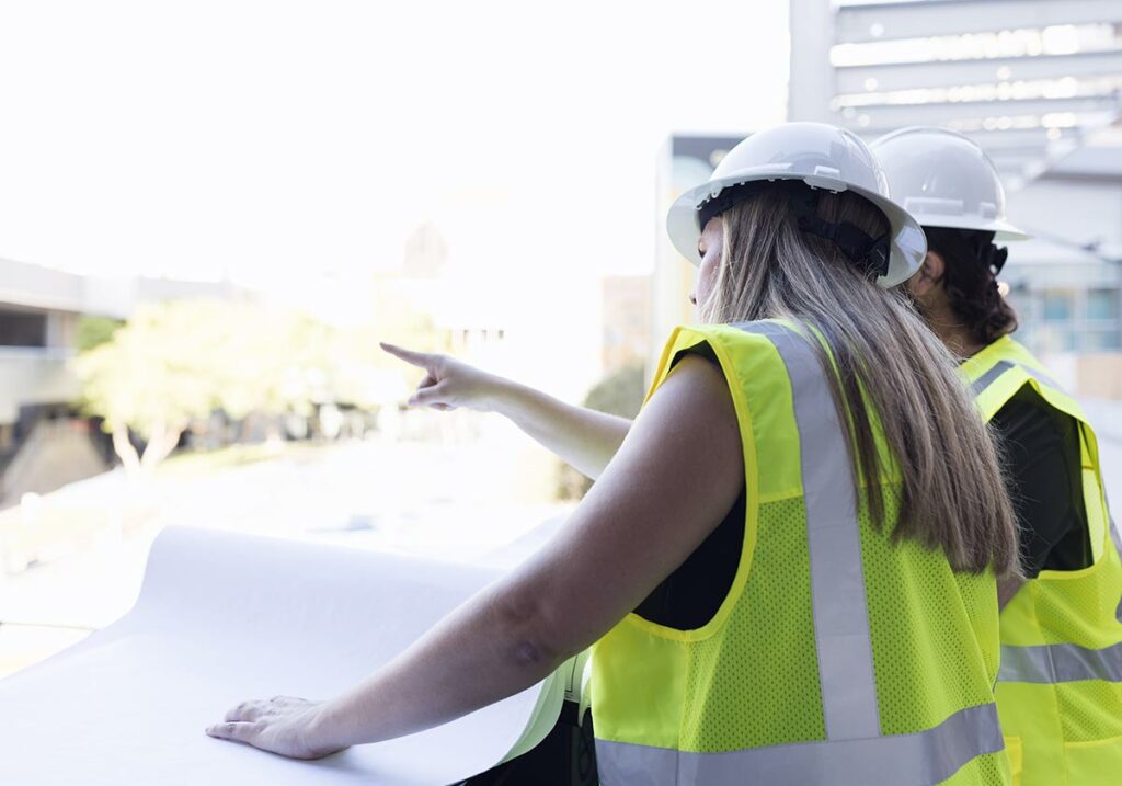 Employee and customer looking at plans on an urban site.